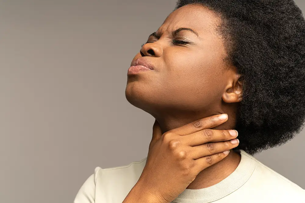 A woman touching her throat and grimacing