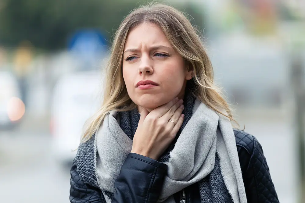 A woman clutching her throat while walking
